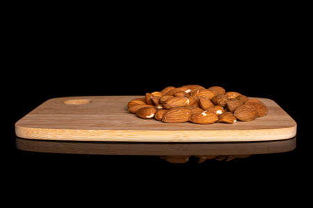 Lot of whole almond on bamboo cutting board on black glassの写真素材
