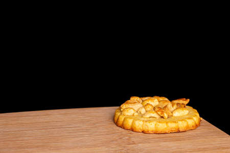 One whole delicious cookie with peanuts on bamboo cutting board on black glass