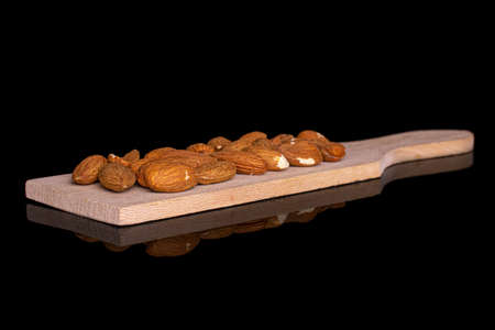 Lot of whole almond on small wooden cutting board on black glass