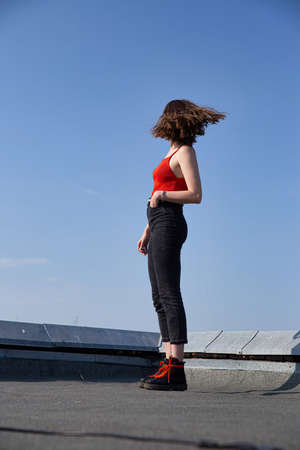 White european woman with dark hair standing on the roof with clear sky behindの写真素材