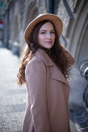 Portrait of pretty woman with curly hair in pastel pink coat outsideの写真素材