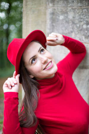 Portrait of smiling white woman with long dark hair in bright red near stone wallの写真素材