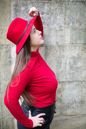 Looking up white woman with long dark hair in bright red near stone wallの写真素材