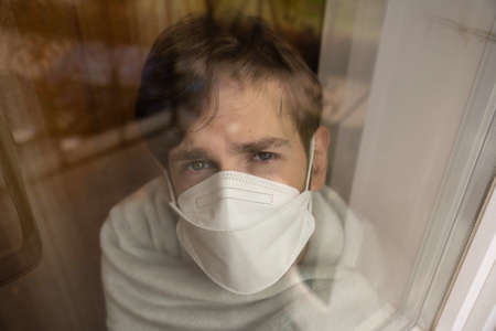 Young handsome tall slim white man with brown hair desperately looking out the window wearing face...