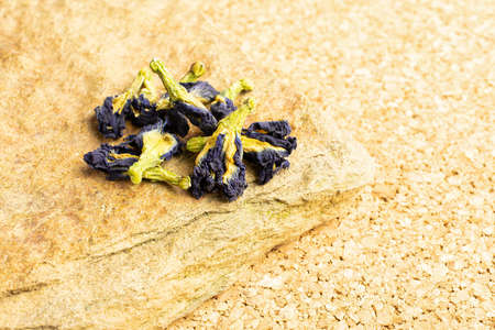Lot of whole dry clitoria ternatea with natural flat rock on cork surface