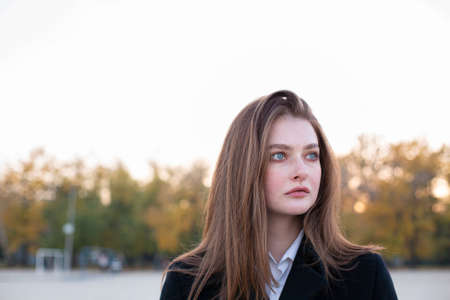 Portrait of pretty long straight haired white european woman in dark coat in autumn on the beach