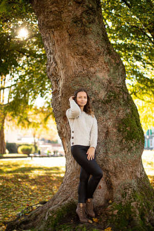 Pretty woman in grey jumper near the tree trunkの写真素材