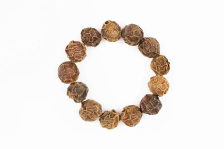 Lot of whole spicy black pepper isolated on white background making a circle shapeの写真素材