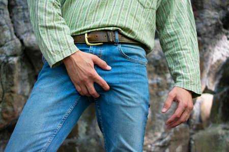 Young white man in blue jeans in green shirt grabbing his crotchの写真素材