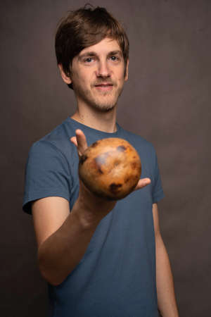 Young handsome tall slim white man with brown hair offering you mate cup in grey shirt on grey backgroundの写真素材