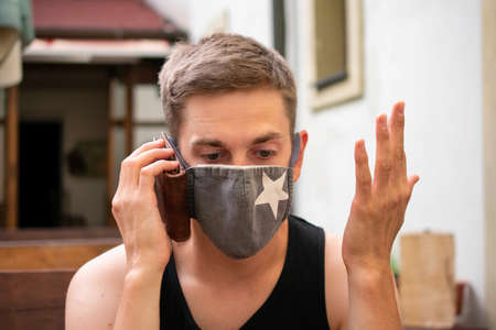 Young handsome white man with brown hair in black undershirt is acting like his wallet is mobile...
