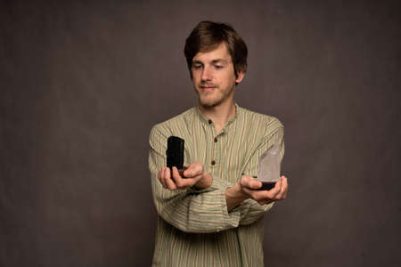 Young handsome tall slim white man with brown hair calmly holding black and white crystals judging...