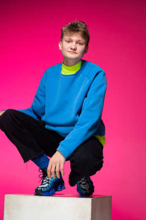Young european boy with white skin isolated on pink with blonde hair sittingの写真素材