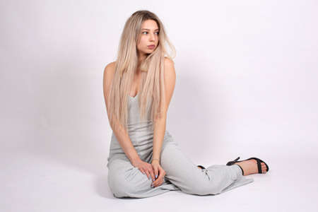 Young european woman with white skin isolated on grey sitting on the floorの写真素材