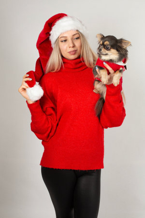 Christmas style in red woman with blonde hair and white skin isolated on grey with a dogの写真素材