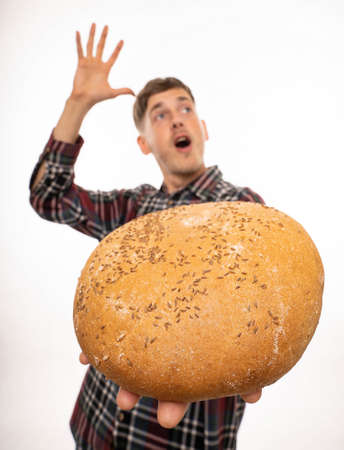 Young handsome tall slim white man with brown hair offering you bread hand in the air in flannel...