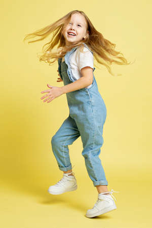 Jumping baby girl with blonde hair isolated on yellow smiling