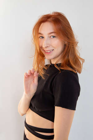 Smiling young woman with red hair isolated on grey