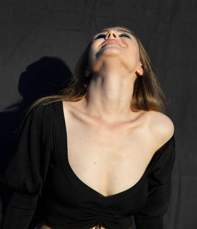 Looking up young woman with white skin isolated on dark brown with deep necklineの写真素材