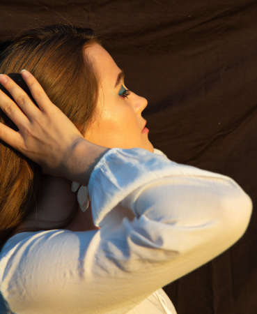 Young woman with white skin isolated on dark brown portrait with raised hand and blue eyeshadow