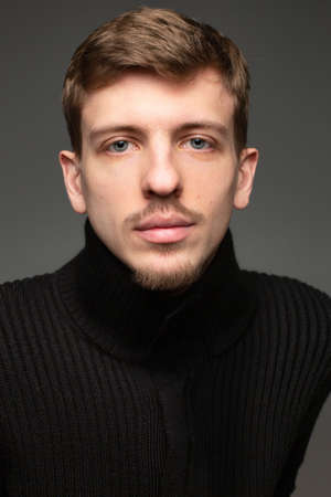 Portrait of young blond european man with short beard and mustache isolated on blackの写真素材