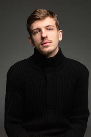 Young blond european man with short beard and mustache isolated on dark greyの写真素材