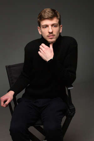 Young blond european man with short beard and mustache isolated on dark grey in total blackの写真素材