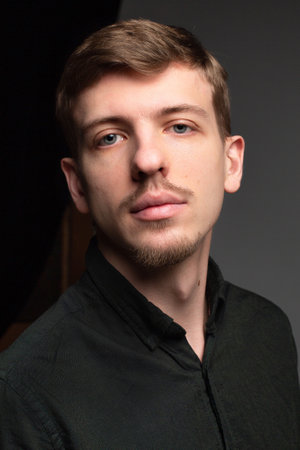 Young blond european man with short beard and mustache isolated on dark grey portraitの写真素材
