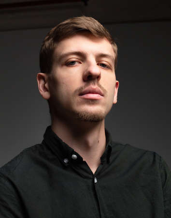 Young blond european man with short beard and mustache isolated on dark greyの写真素材