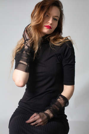 White young european woman in total black isolated on grey in glovesの写真素材