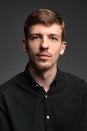 Young blond european man with short beard and mustache isolated on dark grey portrait in total blackの写真素材