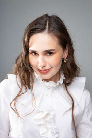 Smiling young woman with long hair with dark brown eyes isolated on greyの写真素材