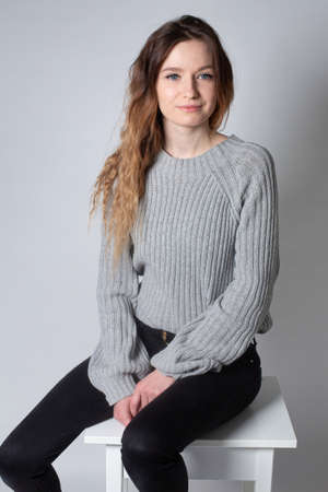 White young european woman with long curly hair in grey knitted jumper isolated on greyの写真素材
