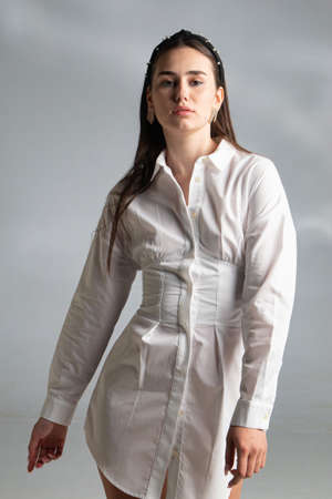 Young woman with dark hair in white long sleeve blouse isolated on greyの写真素材