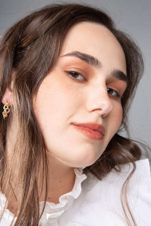 Smiling young woman with long hair with dark brown eyes isolated on grey portraitの写真素材