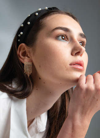 Portrait of young woman with dark hair in white long sleeve blouse isolated on greyの写真素材