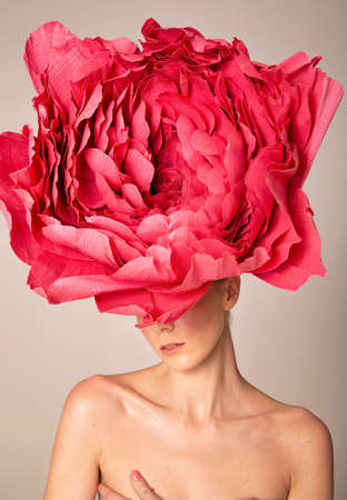 Portrait of young woman wearing pink peony hat isolated on dark beigeの写真素材