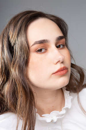 Portrait of young woman with long hair with dark brown eyes isolated on greyの写真素材