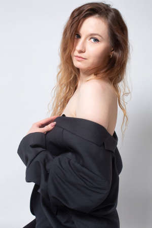 White young european woman with open shoulders in total black isolated on light greyの写真素材