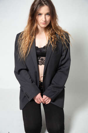 White young european woman with long curly hair isolated on grey in black jacket