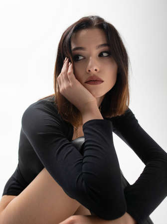 Portrait of slim young woman with short dark hair in black clothes isolatedの写真素材