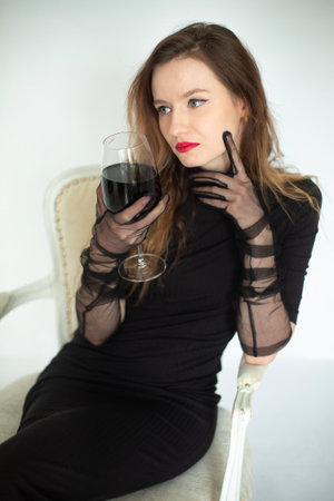 White young european woman sitting isolated on grey and holding a glass of wineの写真素材