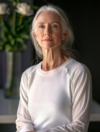 Elegant elderly woman with long gray hair wearing a white shirtの素材