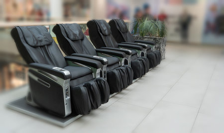 Row of Black Massage Chairs in Shopping Mall Relaxation Zone stock photoの写真素材