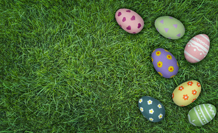 Colorful decorated Easter eggs arranged on vibrant green grass, showcasing various patterns and...