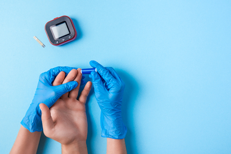 Nurse making a blood test with lancet. Man's hand with red blood drop with Blood glucose test strip and Glucose meter. Copy space. Top viewの写真素材