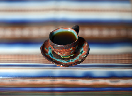 A cup with a delicious fragrant coffee costs on a glass table. Ceramic coffee cups by hand. The service from the blue-beige ceramic.の写真素材