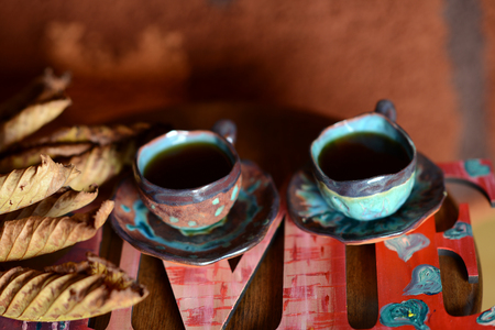 Violinist figurine standing next to a wooden stand on which stand a cup of coffee and chocolate. A cup with a delicious coffee costs on a glass table. Ceramic coffee cups by hand.の写真素材