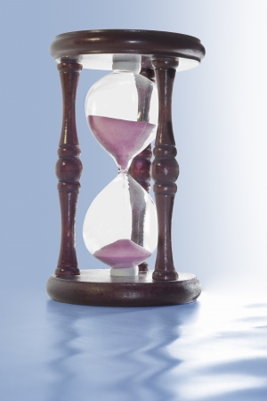 wooden hourglass with pink sand are on a blue background