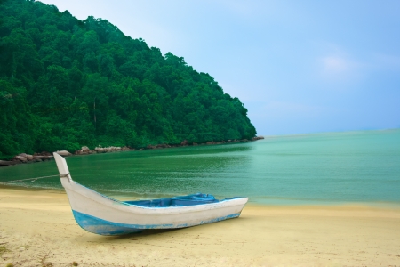 boat on the sandy shore of a tropical island on the background of water and treesの写真素材